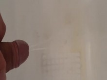 Hombre caliente orinando en la bañera con una doble corriente de erección
